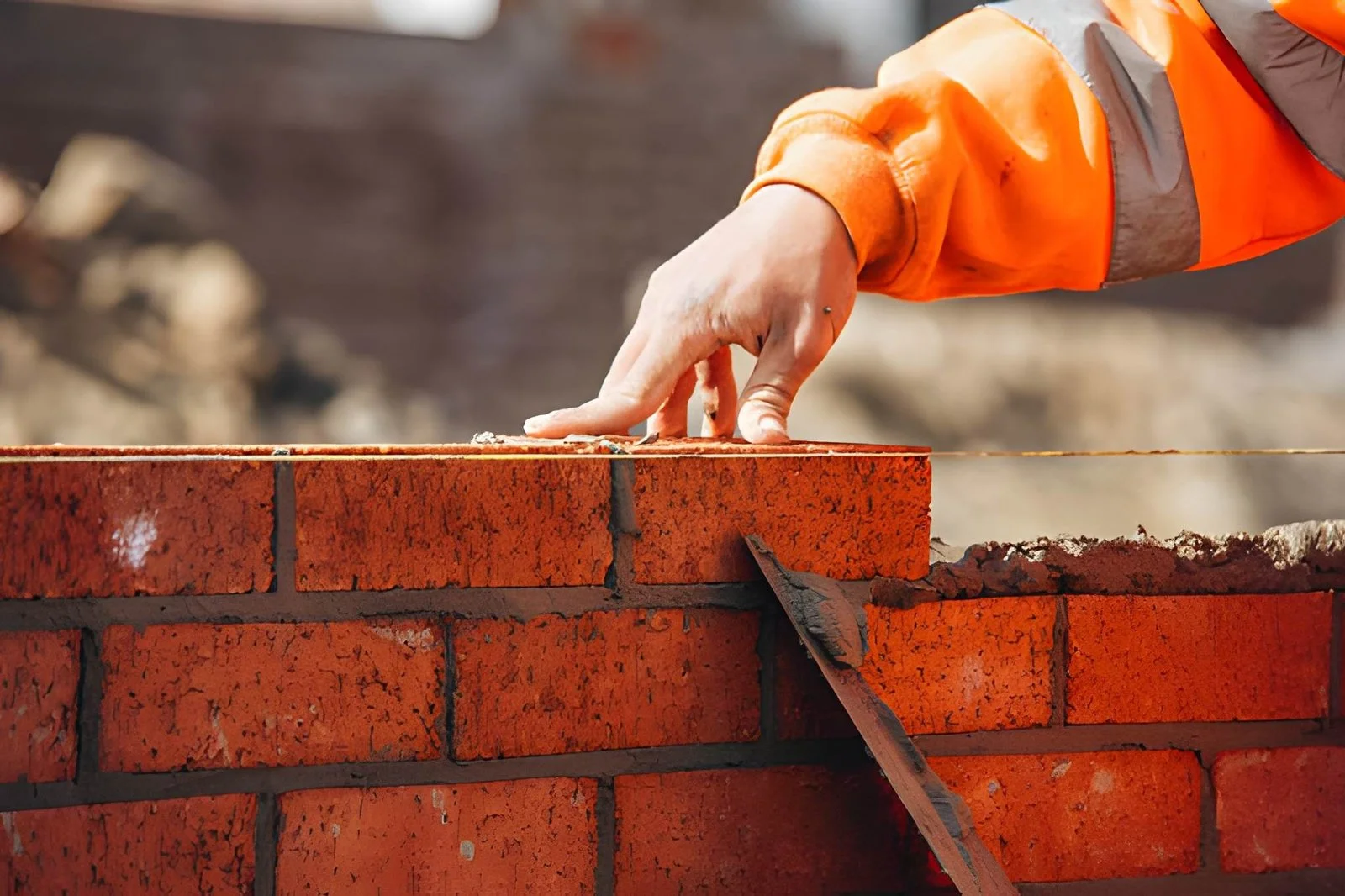 Brickwork contractor NYC laying brick on fresh mortar bed during wall construction