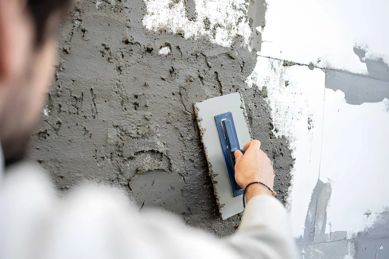 Contractor troweling fresh stucco base coat on exterior wall